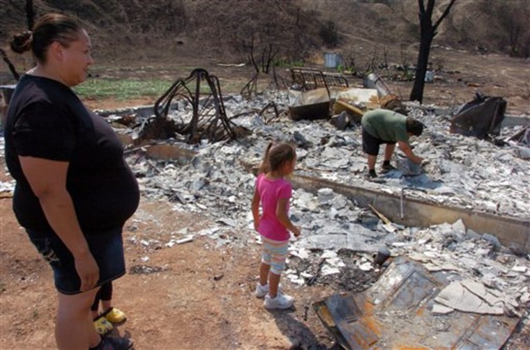 LuAnna Fox and three-year-old daughter Kamille watch her 10-year-old son Sheldon look for salvageable items from the ruins of the family's house on the Northern Cheyenne Indian Reservation in this Aug. 9 photograph.